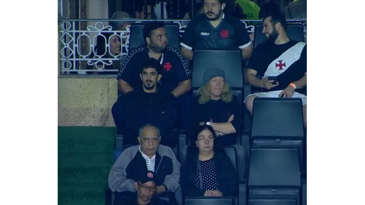Foto: (Reprodução/Premiere) - Janick Gers, de touca, representou o Iron Maiden ao assistir ao jogo do Vasco em São Januário nesta quarta (31)