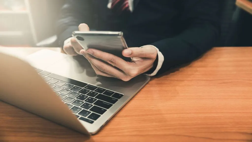 A imagem mostra um homem usando o app da Novibet no celular e no laptop, mostrando que é versátil para diferentes dispositivos.