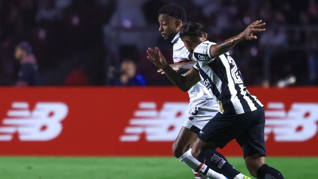A imagem mostra dois jogadores de futebol no meio de uma partida.
