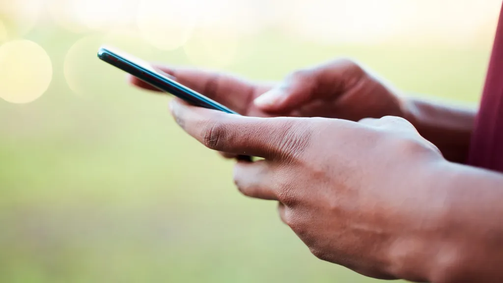 A foto é de um homem com o celular nas mãos fazendo verificação e identificação da conta na Brazino777.