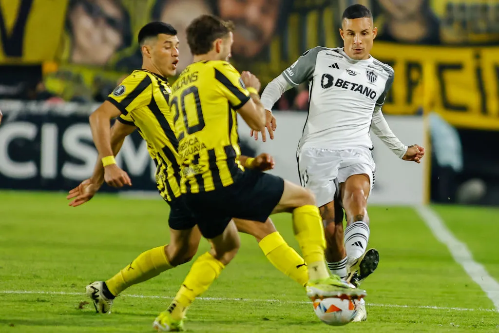 MONTEVIDEO, URUGUAY – MAY 14: Guilherme Arana of Atletico Mineiro passes the ball past Pedro Milans (C) of Peñarol during a Copa CONMEBOL Libertadores 2024 Group G match between Peñarol and Atletico Mineiro at Campeón Del Siglo Stadium on May 14, 2024 in Montevideo, Uruguay. (Photo by Ernesto Ryan/Getty Images)