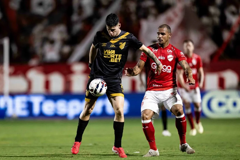 Jogador do Vila Nova-GO disputa lance com  Bruno Zapelli jogador do Athletico-PR durante partida no estadio Onesio Brasileiro Alvarenga pelo campeonato Brasileiro B 2025. Foto: Heber Gomes/AGIF