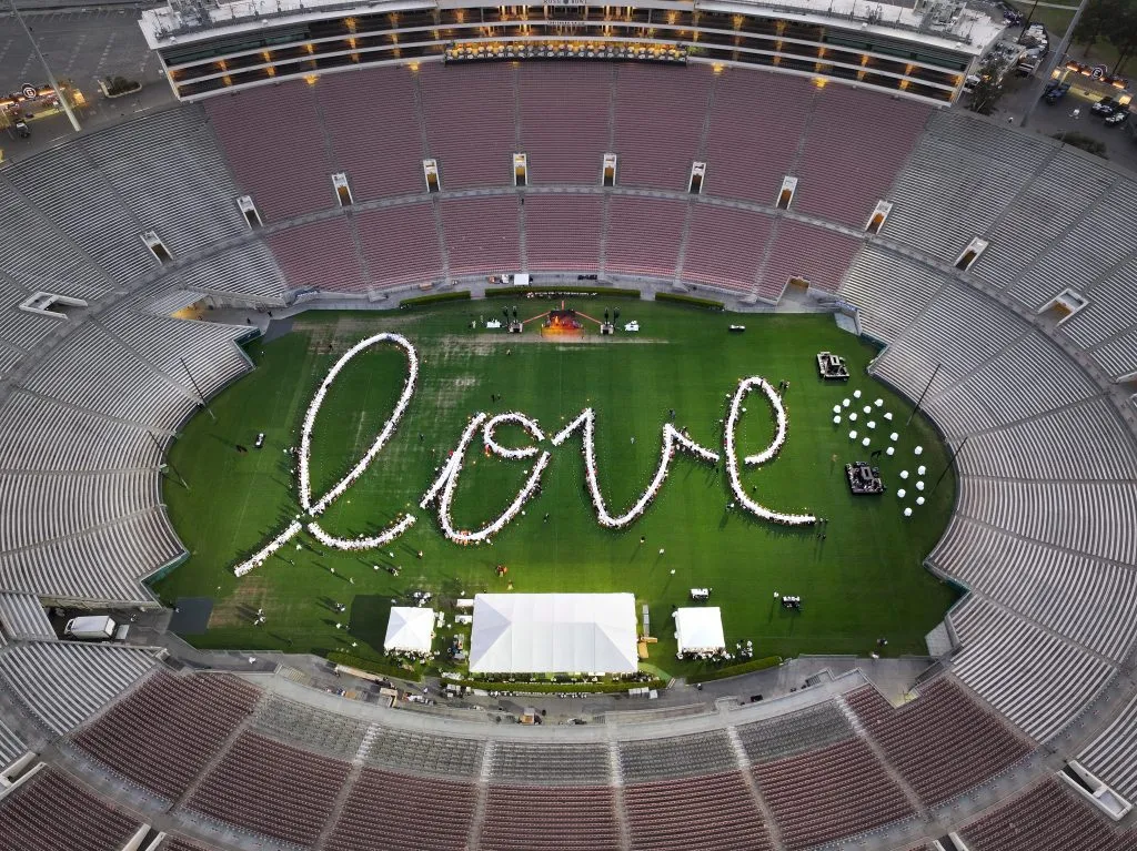 Em uma vista aérea, pessoas participam de um jantar comunitário para 1.000 pessoas no Estádio Rose Bowl em apoio às comunidades afetadas pelos incêndios de Eaton e Palisades em 08 de março de 2025 em Pasadena, Califórnia. O evento “O Dia Depois de Amanhã” reuniu apoiadores, socorristas e membros da comunidade impactados, com toda a renda revertida para o Palisades Community Fund e o Altadena Community Fund. A arrecadação de fundos foi produzida pela Outstanding in the Field. (Foto de Mario Tama/Getty Images)