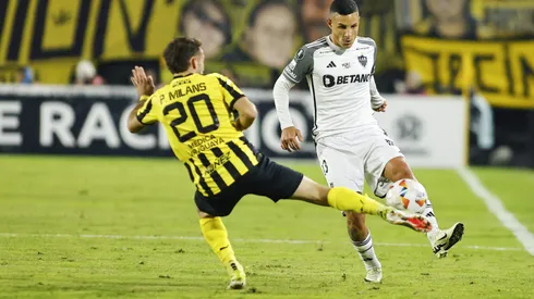 MONTEVIDEO, URUGUAY – MAY 14: Guilherme Arana of Atletico Mineiro passes the ball past Pedro Milans of Peñarol during a Copa CONMEBOL Libertadores 2024 Group G match between Peñarol and Atletico Mineiro at Campeón Del Siglo Stadium on May 14, 2024 in Montevideo, Uruguay. (Photo by Ernesto Ryan/Getty Images)