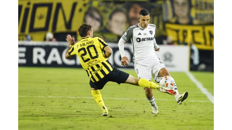 MONTEVIDEO, URUGUAY - MAY 14: Guilherme Arana of Atletico Mineiro passes the ball past Pedro Milans of Peñarol during a Copa CONMEBOL Libertadores 2024 Group G match between Peñarol and Atletico Mineiro at Campeón Del Siglo Stadium on May 14, 2024 in Montevideo, Uruguay. (Photo by Ernesto Ryan/Getty Images)