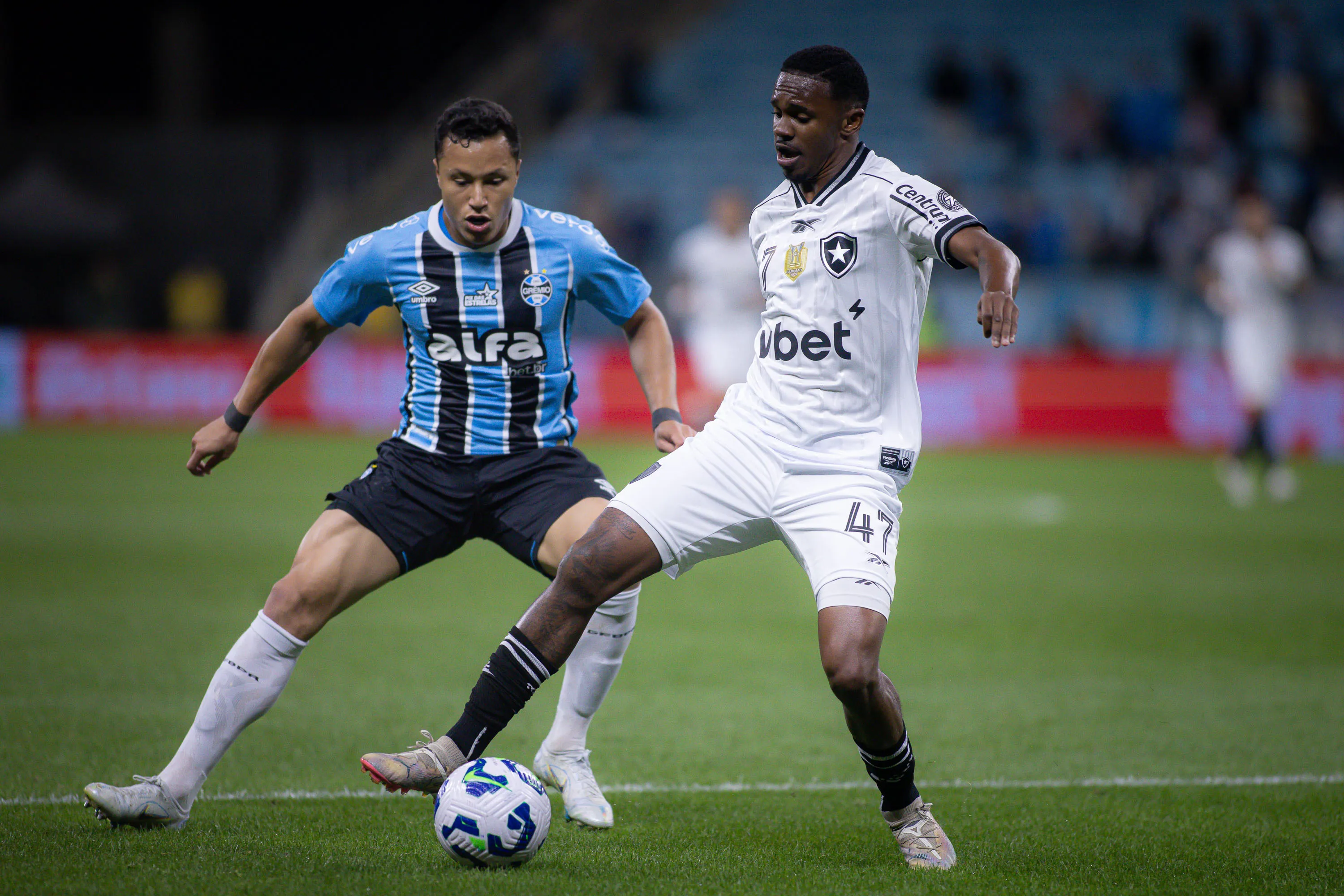Marlon jogador do Gremio disputa lance com Jeffinho jogador do Botafogo durante partida no estadio Arena do Gremio pelo campeonato Brasileiro A 2025. Foto: Maxi Franzoi/AGIF