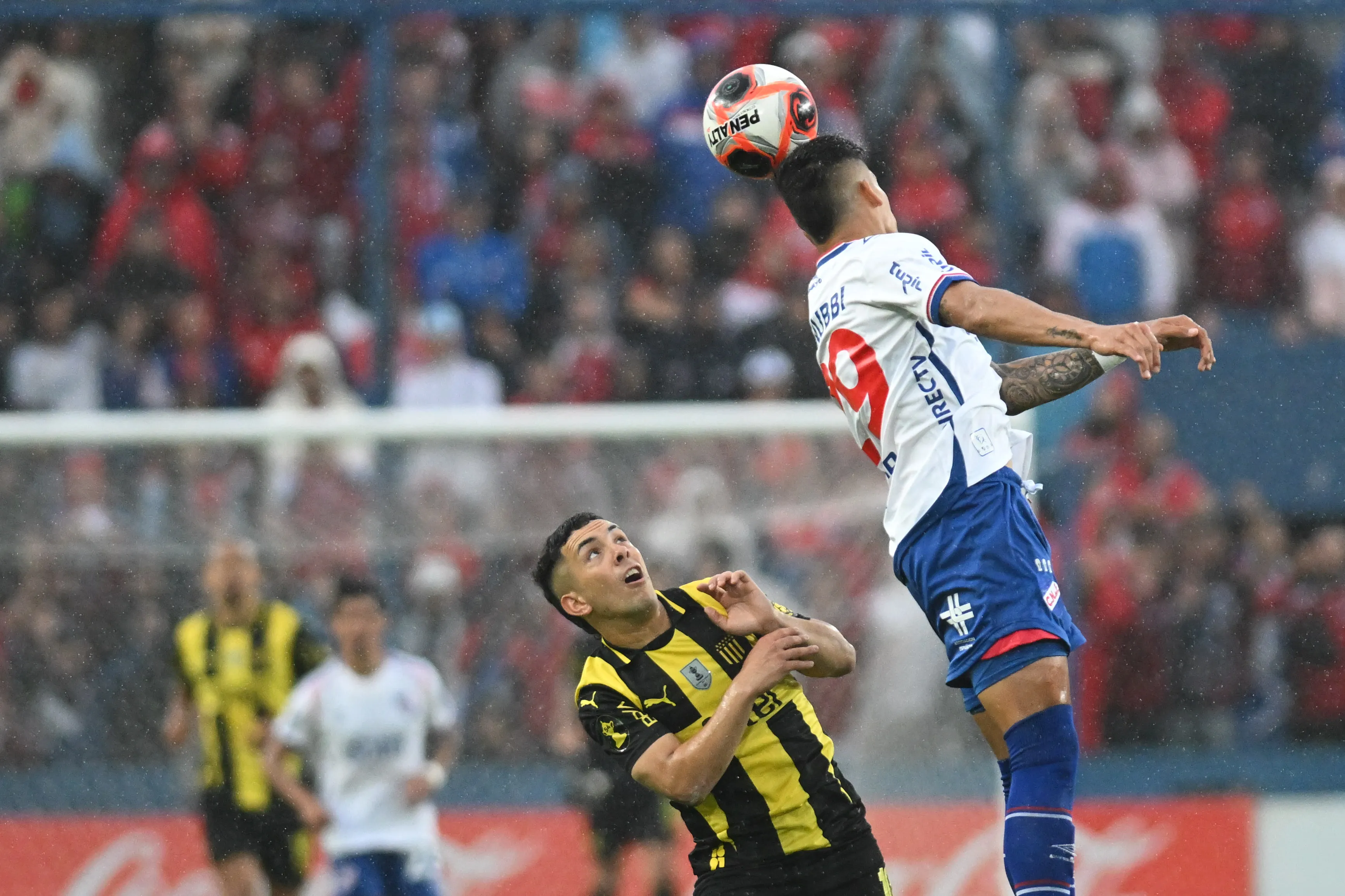 MONTEVIDEO, URUGUAY – NOVEMBER 30: Julian Millan of Nacional heads the ball next to Leonardo Fernandez of Peñarol during the Campeonato Uruguayo 2025 second leg final match between Nacional and Peñarol at Gran Parque Central stadium on November 30, 2025 in Montevideo, Uruguay. (Photo by Guillermo Legaria/Getty Images)