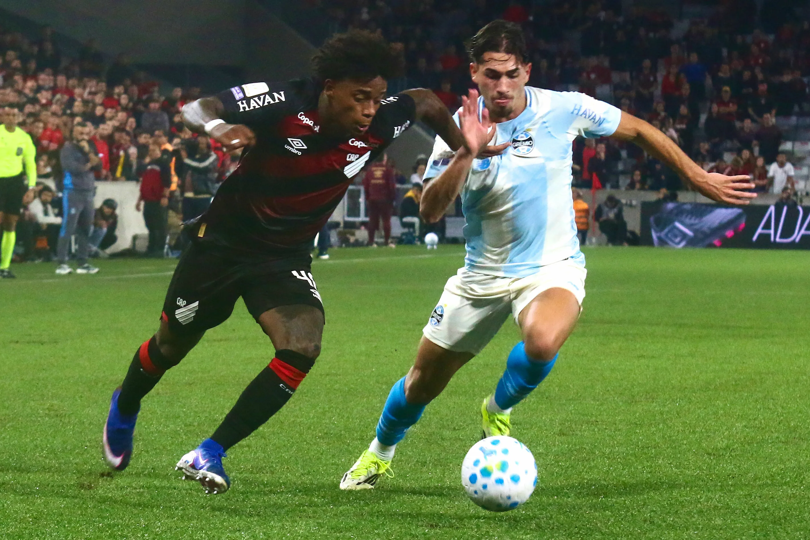 Bruninho jogador do Athletico-PR disputa lance com Pedro Gabriel jogador do Gremio durante partida no estadio Arena da Baixada pelo campeonato Brasileiro A 2026. Foto: Gabriel Machado/AGIF
